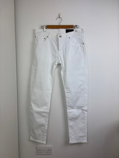 Light blue jeans hanging on a wooden hanger against a plain wall.